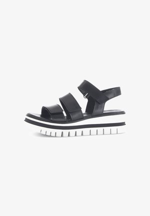 Zwarte leren sandalen met drie verstelbare banden, een gevoerd voetbed en een witte geribbelde plateauzool met een zwarte streep.