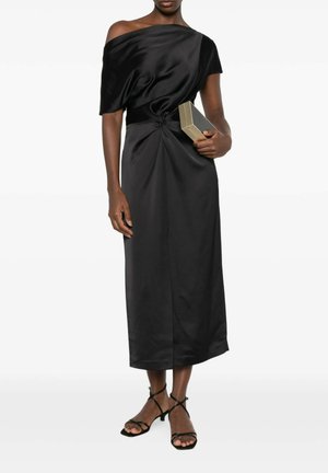 Donna che indossa un abito midi nero monospalla con vita arricciata, tiene una clutch rettangolare e indossa tacchi neri con cinturini.