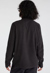 Schwarzer Fleece-Pullover mit langen Ärmeln, hohem Ausschnitt und weicher Textur. Keine sichtbare Markenkennzeichnung, nahtloses Design und lässige Passform.