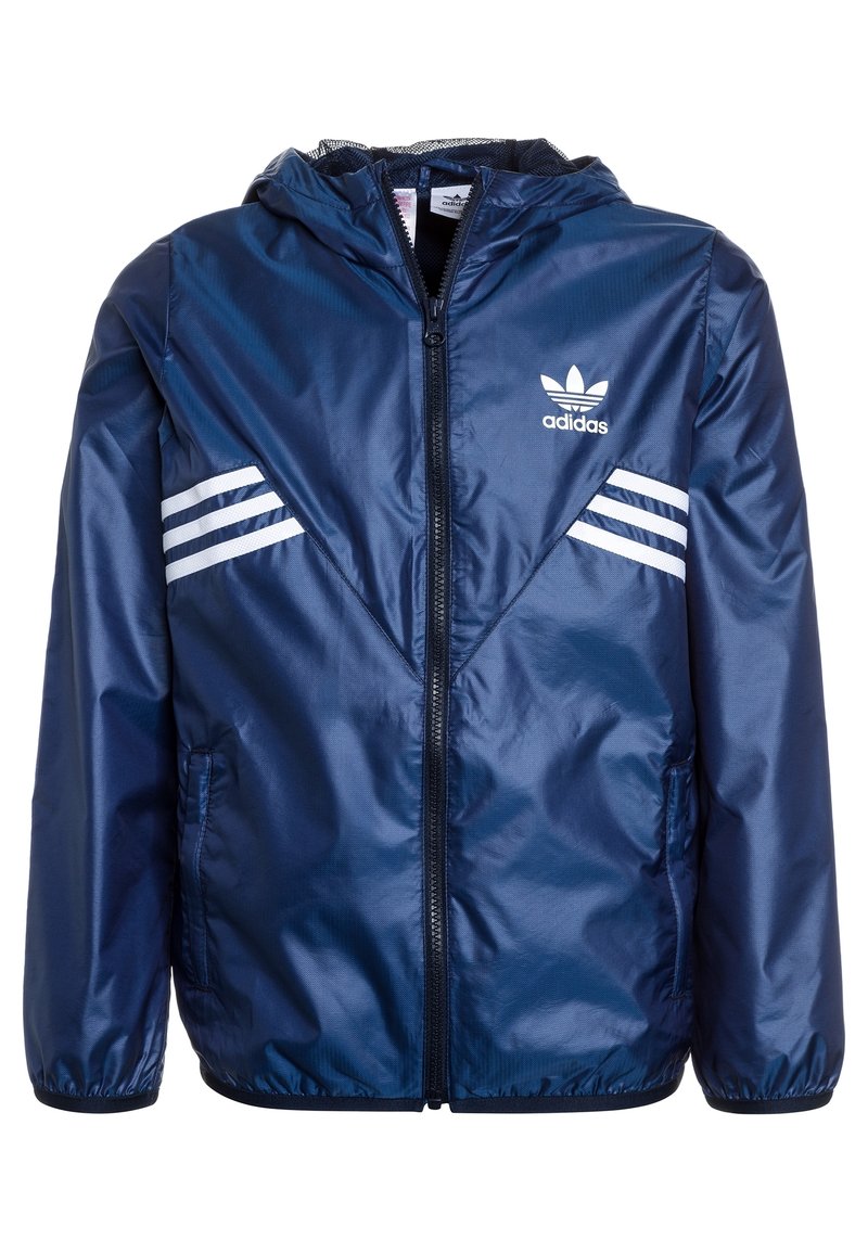 Merinoväri tuulenpitävä takki, joka on valmistettu kiiltävästä nailonista. Takissa on huppu, etuvetoketju ja valkoiset raidat olkapäillä.