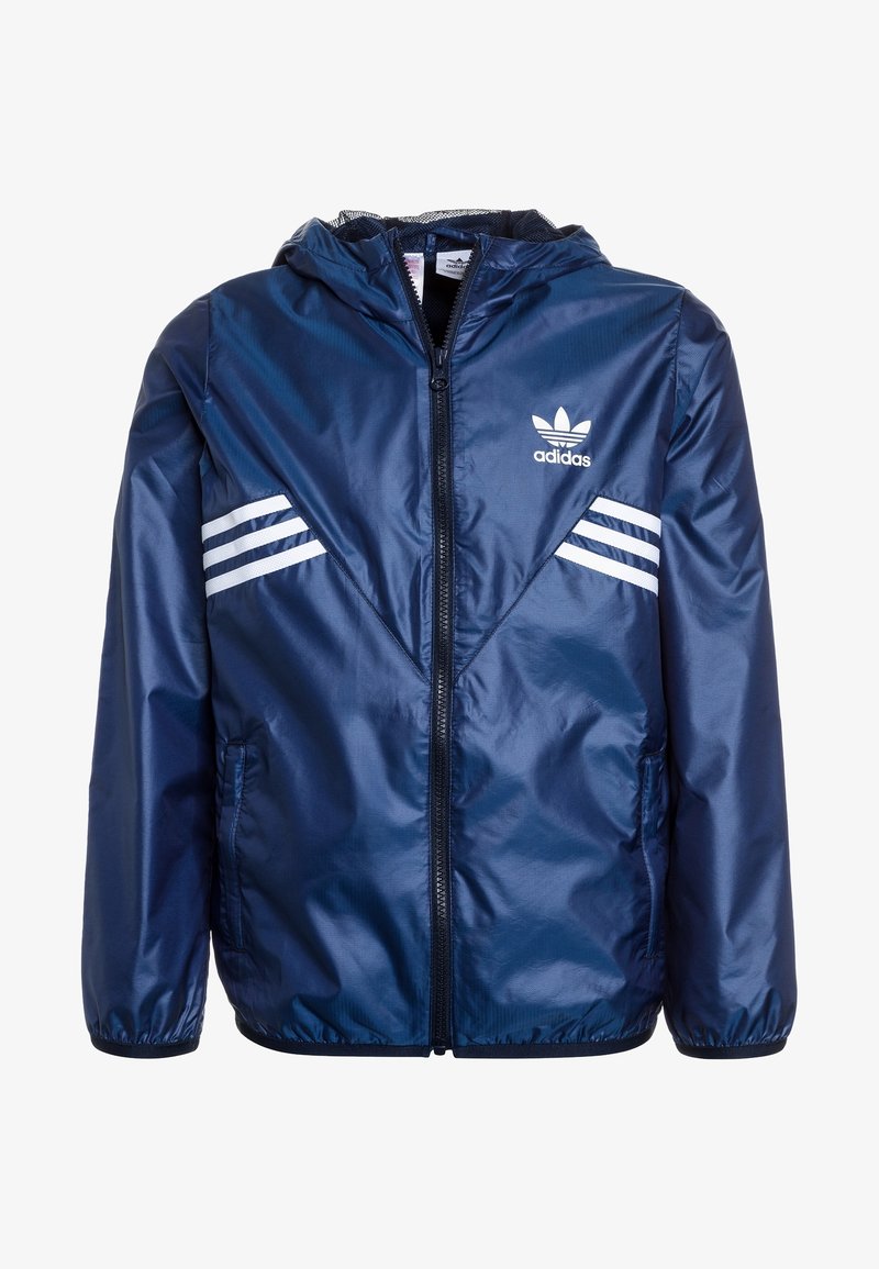 Marinblå vindjacka i glänsande nylon, utrustad med huva, framzipper och vita randiga detaljer på axlarna.