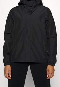Chaqueta impermeable negra con cierre de cremallera al frente, puños elásticos y capucha ajustable. Cuenta con bolsillos laterales y una textura ligera y suave.