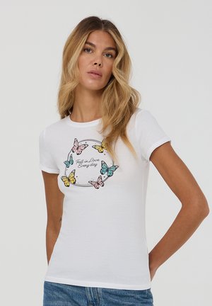 T-shirt bianco in cotone con maniche corte, caratterizzato da una stampa colorata di farfalla e la scritta "Innamorati ogni giorno" al centro.