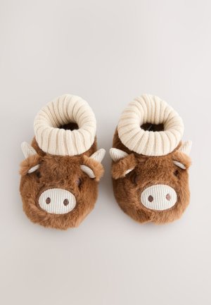 Bruine pluche slippers met een koeienontwerp, voorzien van een geribbelde crème manchet, zachte textuur en geborduurde gezichtsdetails.