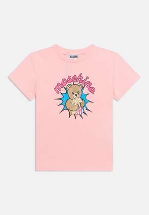 T-shirt rose à manches courtes avec un ours en dessin animé tenant du pop-corn et le mot "moschino" en rose au-dessus d'une explosion étoilée bleue.