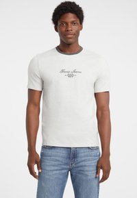 Světle šedé tričko s kontrastním tmavě šedým výstřihem, se znakem "Guess Jeans" v černé barvě, krátké rukávy, přiléhavý střih, volnočasový styl.