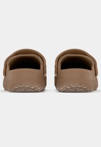 Bottines marron à enfiler avec une forme arrondie, fabriquées en caoutchouc texturé. Équipées d'une lanière arrière et d'une semelle à motifs. Design minimaliste.