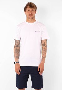 T-shirt en coton blanc avec un col rond, des manches courtes et un graphique coloré de palmier sur la poitrine gauche.