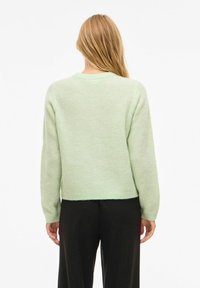 Piparmētru zaļa adīta džemperis ar apaļu kakla izgriezumu, garām piedurknēm un īsu apakšmalu, veidots ar teksturētu audumu un mīkstu apdari.