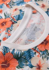 Bloemen T-shirt met een witte ronde hals, lichte stof met oranje en roze hibiscusbloemen, groene bladeren en een zachte textuur.
