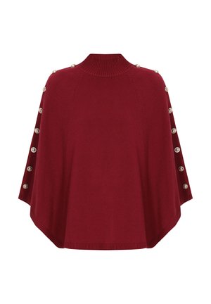 Puncho merah rajutan dengan leher tinggi, menampilkan kancing dekoratif di sepanjang bahu dan hem yang melengkung. Tekstur halus dan potongan yang santai.