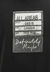 Black cotton t-shirt featuring a printed graphic resembling a concert pass, with text "ALL AREAS," "OASIS," "London," and "16th Aug."