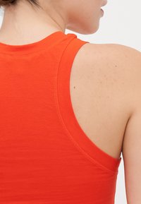 Orange sleeveless top with a round neckline, made of smooth fabric. The back features a curved cut and visible stitching details.