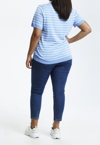 Lys blå stribet t-shirt med korte ærmer, parret med mørkeblå skinny jeans og hvide atletiske sko.