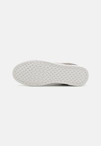 Semelle de basket avec une base en caoutchouc blanc et un motif en diamant texturé, dotée d'une partie supérieure lisse grise avec des accents visibles minimaux.