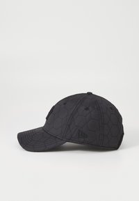 Black quilted cap with hexagonal pattern, curved brim, and black accents. Features a raised logo on the side and six ventilation holes.