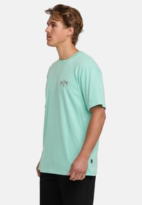 Mint green short-sleeve t-shirt made of soft cotton, featuring a round neckline and a logo printed on the upper chest area.