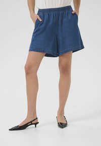 Denim šorti ar elastīgu jostasvietu, sānu kabatām un brīvu piegriezumu. Tumši zilā krāsā ar kontrastējošiem izšuvumiem un ikdienišķu dizainu.