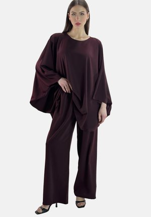 Ensemble de salon bordeaux comprenant un haut ample et drapé avec des manches larges et un pantalon à jambes larges assorti, fabriqué dans un tissu lisse.