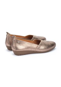 Bailarinas metálicas bronce con un acabado texturizado, punta redonda y perfil bajo; acentuadas con un detalle de logo en el lateral y una suela acolchada.