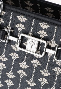 Borsa nera in tessuto con motivo floreale in crema. Presenta accessori in acciaio inox e una chiusura rettangolare con un emblema floreale.
