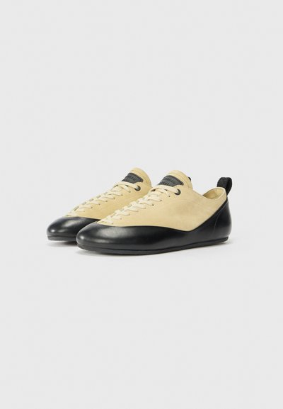 Zapatos de escalada con un upper de ante amarillo y una puntera de goma negra; cuentan con cordones planos y una pestaña en el talón para facilitar su uso.