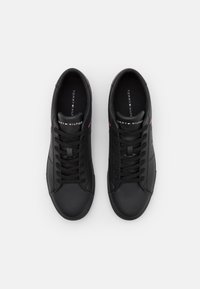 Schwarze Leder-Sneaker mit runden Zehen, flachen Schnürsenkeln und markierten Innensohlen. Mit roten und weißen Akzenten an den Seiten.