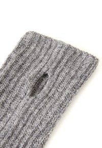 Calcetín de lana gris con una textura acanalada y un pequeño agujero cerca de la parte superior. La tela parece suave y gruesa, adecuada para mantener el calor.