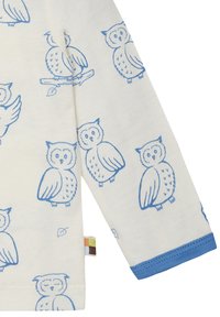 Camicia a maniche lunghe in cotone crema con stampe di gufi blu, polsini a coste blu e un piccolo etichetta colorata all'orlo.