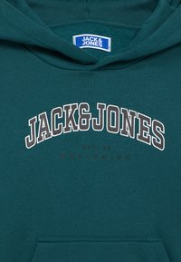 Teal hoodie with "JACK & JONES" in large white-outlined letters, smaller text "EST. 90 WORLDWIDE" below, and front pocket visible.