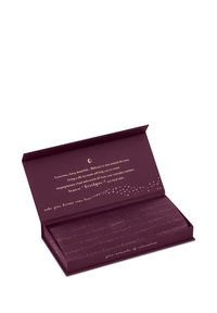 Paarse open doos met een opgevouwen zijden oogmasker erin, gouden tekst die het gebruik beschrijft voor de delicate huid rond de ogen en bevordert ontspanning.