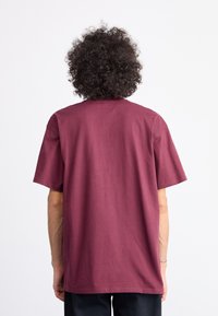 Maroon cotton t-shirt with a relaxed fit, short sleeves, and a crew neck. Smooth texture, simple design, and no visible patterns or hardware.