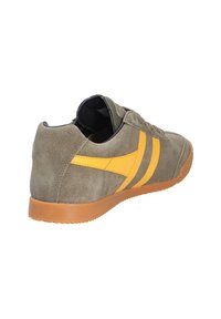 Baskets en daim vert olive avec des bandes latérales jaunes, semelle en caoutchouc marron et intérieur noir, vues de dos et de côté sur fond blanc.