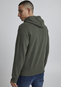 Hooded sweatshirt in olive green cotton blend, featuring a ribbed hem and cuffs, with a textured surface and casual fit.