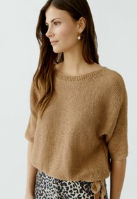 Hellbrauner, lockerer Strickpullover mit weitem Ausschnitt und kurzen Ärmeln, kombiniert mit gemusterten Hosen im Leopardenprint mit Bindebändern.