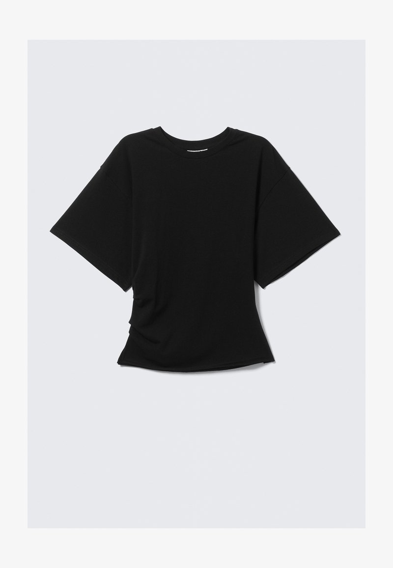 T-shirt nera oversize a maniche corte con collo rotondo e vita leggermente aderente su uno sfondo chiaro.