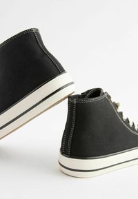 Czarne sneakersy za kostkę z materiału kanvas, z białym przeszyciem i gumową podeszwą. Posiadają okrągłe sznurówki oraz kontrastowy biały pasek.
