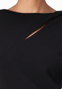 Musthave mustärk, millel on lõhestatud kaelus ja kontrastne sisemine kiht. Sile kangastekstuuri ja minimalistliku kujundusega ning puhaste joontega.