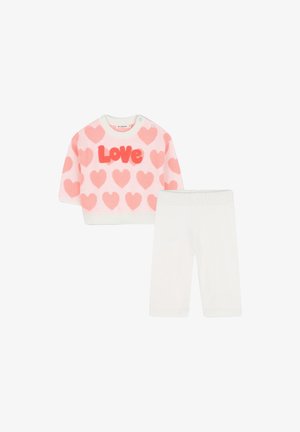 Ensemble en tricot composé d'un pull rose à manches courtes avec des motifs de cœurs et le texte "Love", associé à un legging blanc.