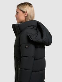 Črni puhovka ima visok ovratnik, žepke z zadrgo in izrazit logotip na rokavu. Teksturno prešito oblikovanje nudi izolacijo.