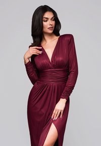 Vestido burdeos de largo completo con un profundo escote en v, mangas largas fruncidas y una abertura lateral, confeccionado en una tela suave y reflectante.