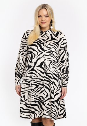Knoopshirt jurk in zwart en crèmekleurig zebra patroon. Heeft lange mouwen, een kraag en een relaxed fit, met een zachte, gestructureerde stof.