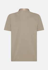 Polo beige con colletto classico, maniche corte e una texture liscia, caratterizzato da un design semplice senza motivi o accenti visibili.