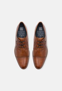 Chaussures habillées en cuir marron avec une finition lisse, à lacets, à bout rond et à couture décorative sur le dessus. Logo de la marque sur la semelle intérieure.