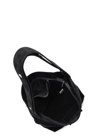 Sac fourre-tout en suède noir avec un intérieur spacieux, comprenant une poche zippée et une texture douce. Deux poignées solides pour le transport.