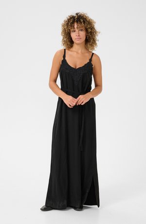 Black maxi dress with lace detailing at the neckline, adjustable straps, and a self-tie waist belt; features a side slit for ease of movement.