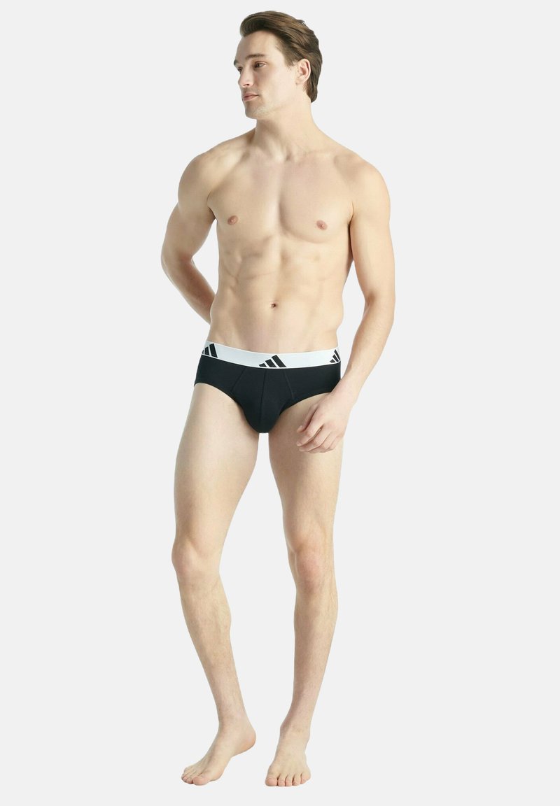 Zwarte herenondergoed met een witte tailleband voorzien van drie zwarte strepen. Gemaakt van gladde stof, de strakke pasvorm accentueert de contour.