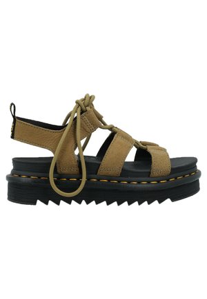 Sandalo in suede tan con lacci regolabili, tacco aperto e suola piatta nera caratterizzata da un motivo zigzag e cuciture di accento giallo.