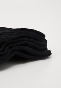 Zwart gebreide wollen stof gevouwen in lagen, met een gladde textuur en een consistent ribbelpatroon.