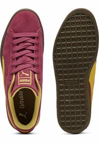 Puma sporta apavi ar bordo zamša virsmu, dzelteniem akcentiem un teksturētu brūnu gumijas zoli ar dimanta rakstu.